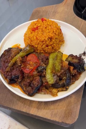 A delicious dish of layered roasted eggplant and spiced ground meat in a glass baking dish.