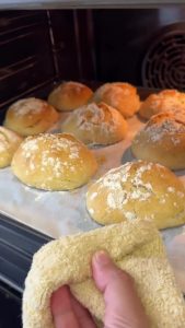 Baking the bread rolls in the oven with a bowl of water for a crispy artisan crust.