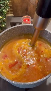 Using an immersion blender to make the red pepper soup smooth.