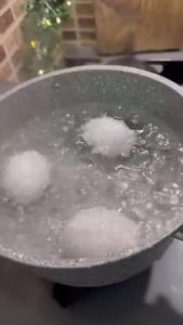Boiling eggs in a pot and cutting them in half for a breakfast recipe.