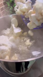 Boiling fresh cauliflower florets in a pot of salted water.