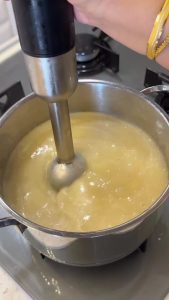 Simmering the vegetables in water until they are tender and ready to be blended.