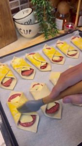 Brushing bright yellow egg yolk over the tops of the raw pastry bites.