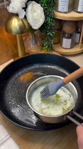 Brushing a large frying pan with melted butter for the börek base.
