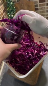 A close-up of purple cabbage turning bright pink during the massage step.