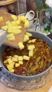 Checking the texture of the potatoes and green beans with a fork in the pot.