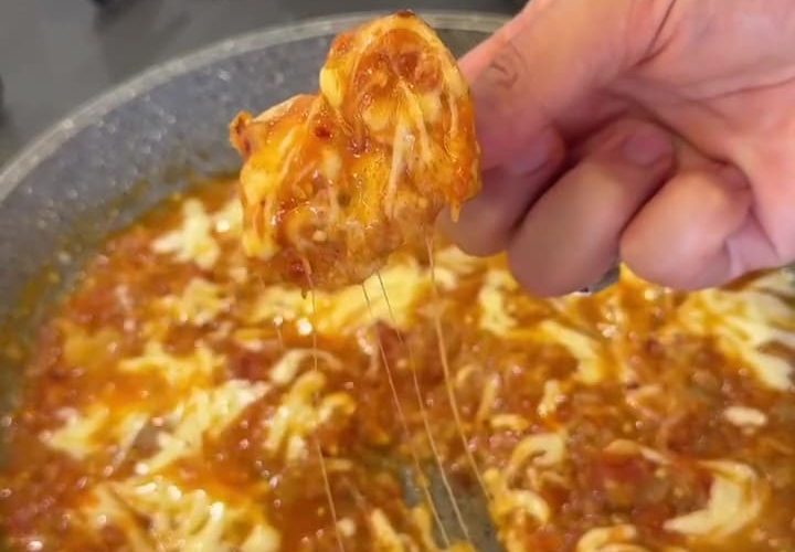 A skillet of mashed tomatoes and eggplant topped with melted kashar cheese.