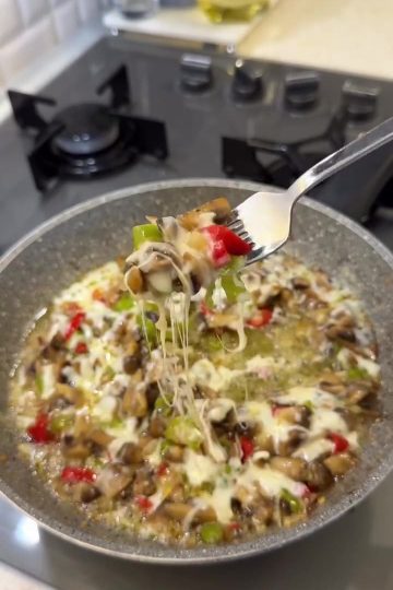 A close-up of sautéed mushrooms and peppers topped with melted, bubbly kashar cheese.