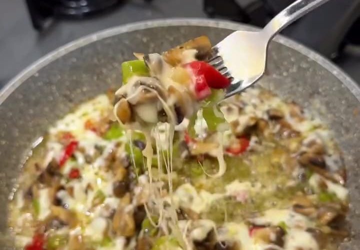 A close-up of sautéed mushrooms and peppers topped with melted, bubbly kashar cheese.