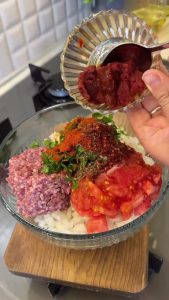 Chopping fresh parsley, onions, and garlic on a wooden cutting board for the dolma filling.