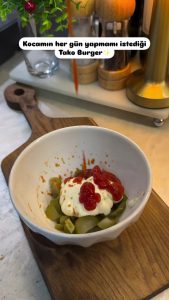 Finely dicing pickled gherkins on a wooden board to prepare the taco sauce.