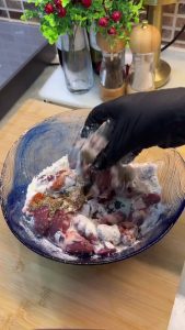 Tossing raw chicken liver pieces in a spiced flour mixture to ensure even coating.