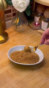 Rolling the glazed cookie balls in a bowl of toasted sesame seeds.