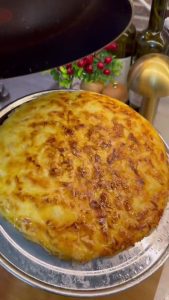 Frying the pan borek on low heat with the lid closed to ensure even cooking.