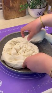Frying the cheese börek on a stovetop with the pan lid closed.