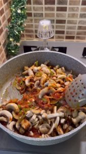 Cooking grated tomatoes in a pan to create a rich base for mushrooms.
