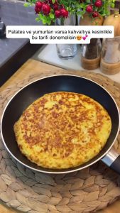 Frying the potato omelet on low heat with a closed lid to cook the center.