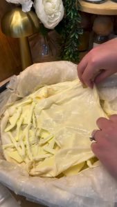 Placing more soaked yufka over the cheese filling to seal the moisture.