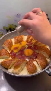 Cracking fresh eggs directly over the cooked sucuk in the middle of the simit ring.