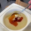 A bowl of silky blended potato and cornmeal soup topped with red pepper butter.