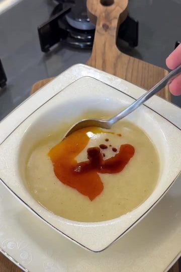 A bowl of silky blended potato and cornmeal soup topped with red pepper butter.