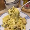A plate of creamy golden curry chicken and mushroom pasta garnished with basil.