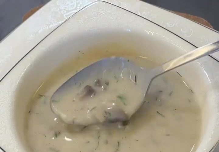 A bowl of creamy mushroom soup garnished with fresh dill and black pepper.