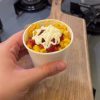 A cup of buttery Turkish street corn topped with ketchup and mayonnaise.