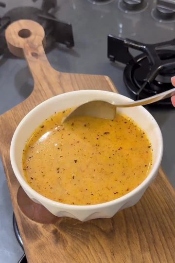 A bowl of creamy vermicelli soup garnished with sizzling mint butter and garlic.