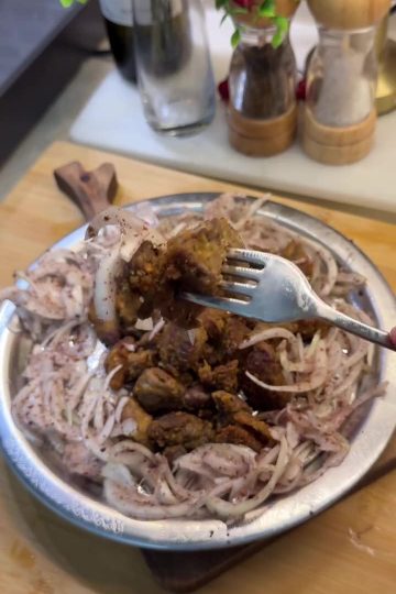 A platter of golden brown crispy fried chicken livers served with onions and lemon.