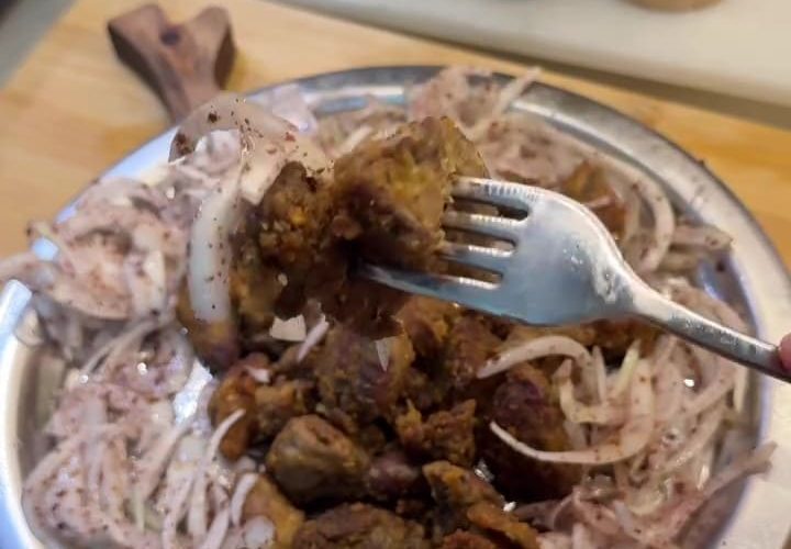 A platter of golden brown crispy fried chicken livers served with onions and lemon.