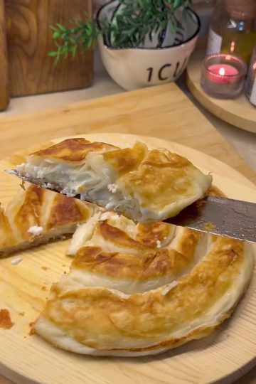 Two golden brown rose-shaped Turkish cheese pastries frying in a pan.