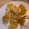 Golden brown crispy fried cauliflower florets served on a plate with a bowl of garlic yogurt.