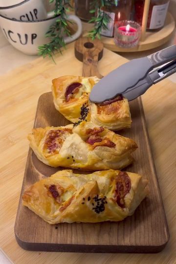 Golden brown crispy puff pastry bites filled with Turkish sucuk and melted cheese on a serving tray.