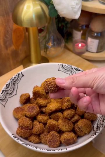 A close-up shot of golden-brown crunchy Turkish sesame bite cookies (Lokmalık Susamlı Kurabiye) served on a plate with a traditional glass of Turkish tea.