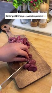 Slicing fresh chicken livers into medium-sized pieces on a clean cutting board.