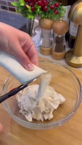Shredding Turkish yufka dough sheets into small pieces with kitchen scissors.