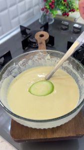 Dipping thin zucchini slices into the thick batter to ensure they are fully coated.