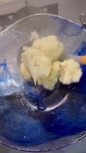 Draining parboiled cauliflower florets to keep them firm for frying.