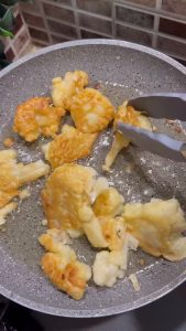 Placing crispy fried cauliflower on paper towels to remove excess oil.