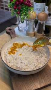 Drizzling the hot, red-tinted butter over a serving of creamy Keşkek.