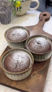 Dusting white powdered sugar over the freshly baked warm chocolate soufflés.
