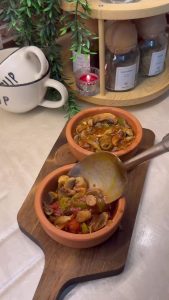 Transferring the cooked mushroom sauté into small individual clay pots.