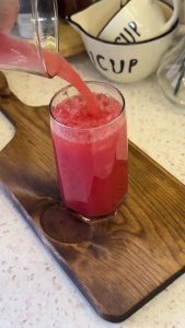 Filling a tall glass with large clear ice cubes to prepare the summer cooler.