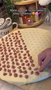 Adding small pieces of spiced ground beef into the pockets of a mantı mold.