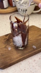 Placing fresh ice cubes into a tall glass for the iced coffee presentation.