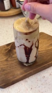 Stirring the honey whipped coffee foam into the milk for a perfect marbled iced coffee.