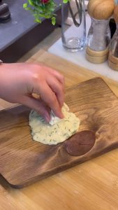 Flattening a walnut-sized piece of dill dough in the palm of the hand.