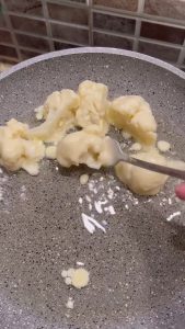 Flipping cauliflower florets in the pan to ensure an even golden brown crunch.
