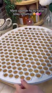 Dusting a honeycomb-shaped mantı mold with flour to prevent sticking.